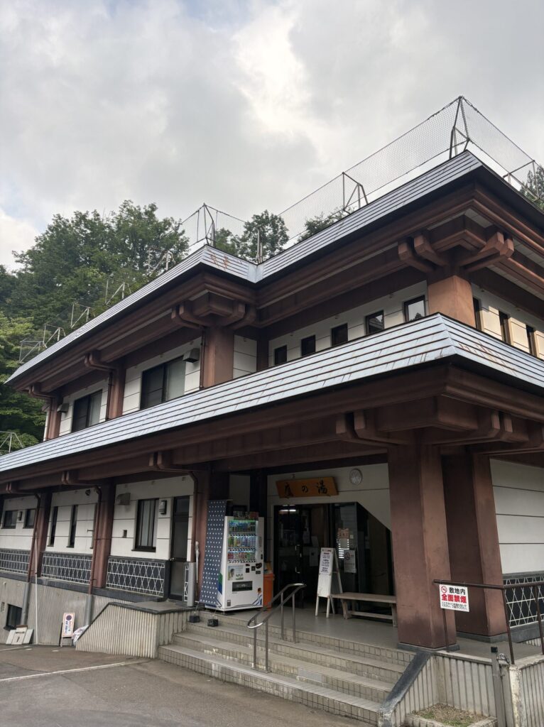 松之山温泉センター鷹の湯の入口。木造二階建てで、屋根に雪囲いの柵が設置されている
