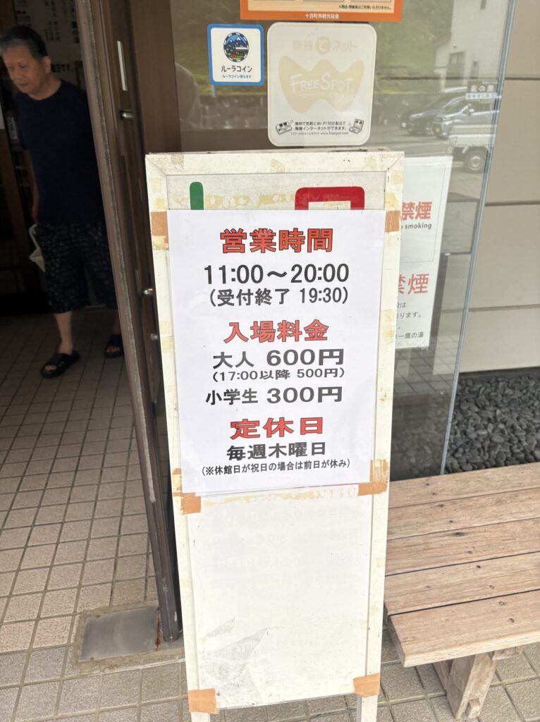 鷹の湯の入口に置かれた案内板。営業時間、入場料金、定休日が書かれている