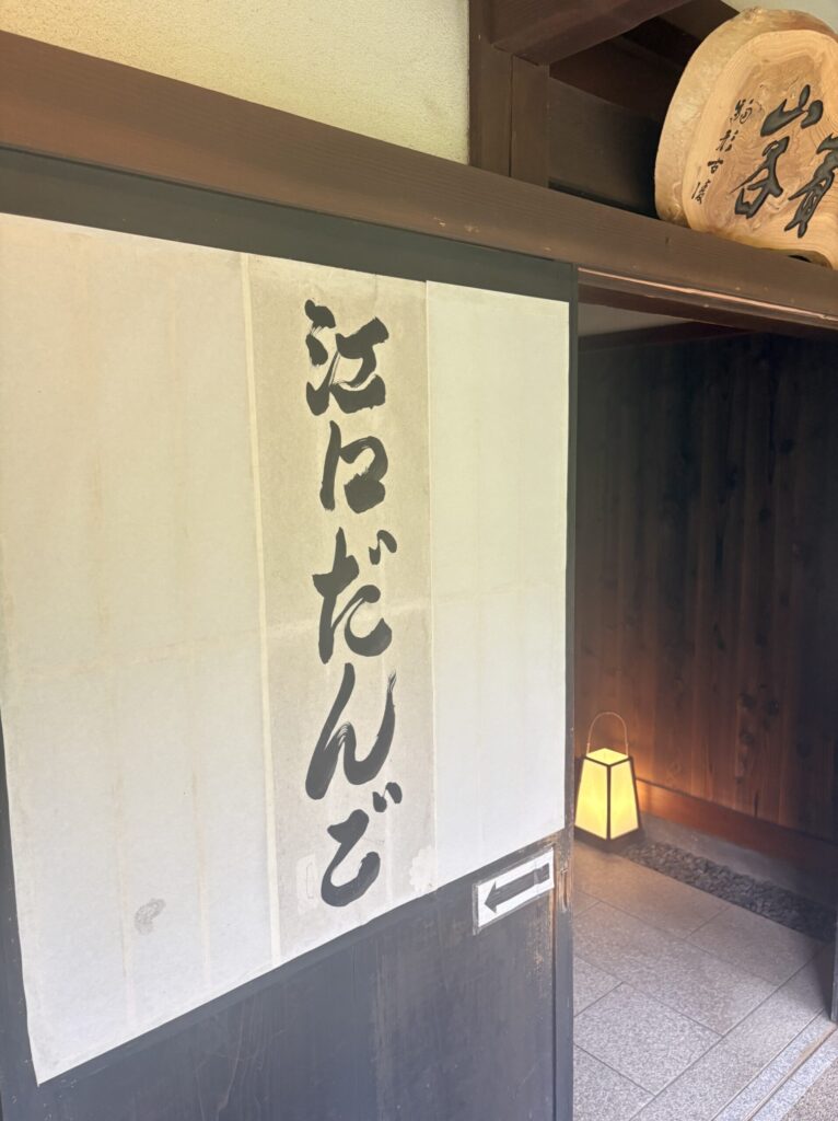 江口だんご本店の入口にかかる白いのれんと行灯