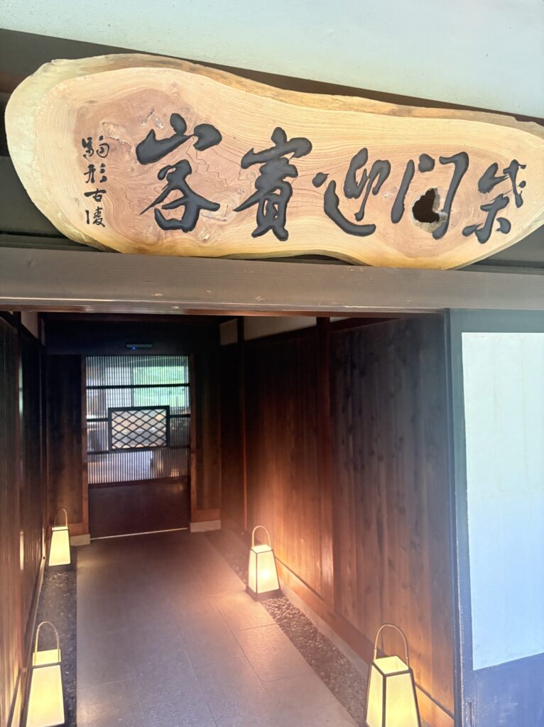 江口だんご本店のけやき一枚板の看板「笑門迎賓客」と行灯が並ぶ通路