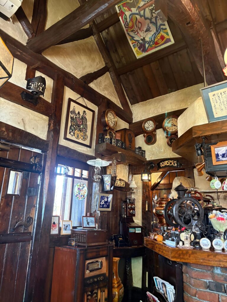 塩沢邪宗門の店内に並ぶ古時計とアンティークカメラ、天井の凧絵
