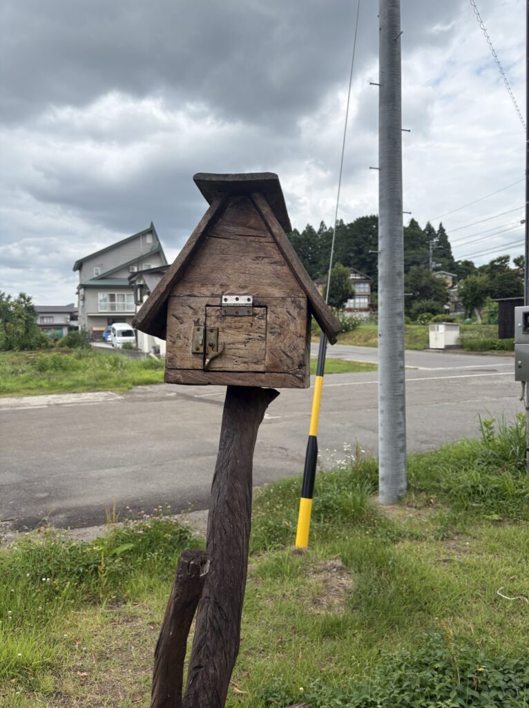 草の中に立つ思い出ポストと、土市駅周辺の舗装されていない道