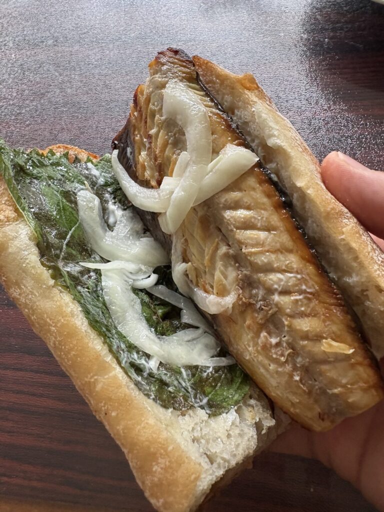 パンと暮らしとヤナギヤの鯖サンドの断面。サバの下に大葉、上に玉ねぎのマリネとレモン